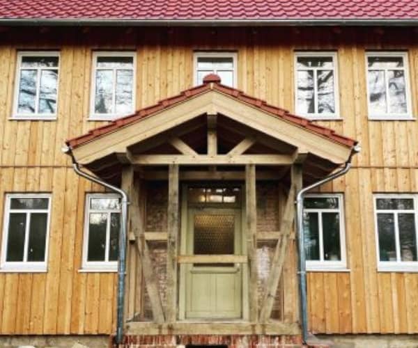 Frontalansicht einer sanierten Fachwerkhaus-Fassade mit traditionellem Holzeingang und neuem Dach, umgesetzt von der Zimmerei Brandt, Experten für Fachwerksanierungen und Dachdecker.