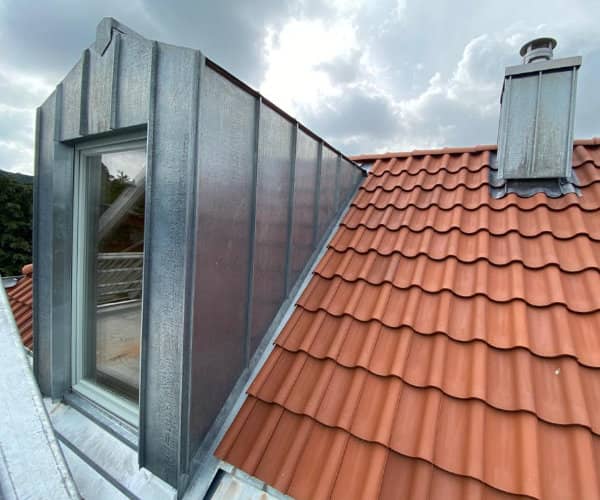 Moderne Dachgaube mit hochwertiger Zinkverkleidung und neuen, roten Dachziegeln, umgesetzt von unserer Dachdeckerei Brandt bei Braunschweig.