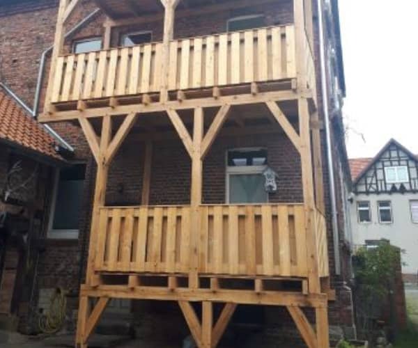 Frontalansicht eines dreistöckigen Holzbalkons in traditioneller Bauweise, hergestellt vom Spezialisten für Holzbau und Dachdeckerei.