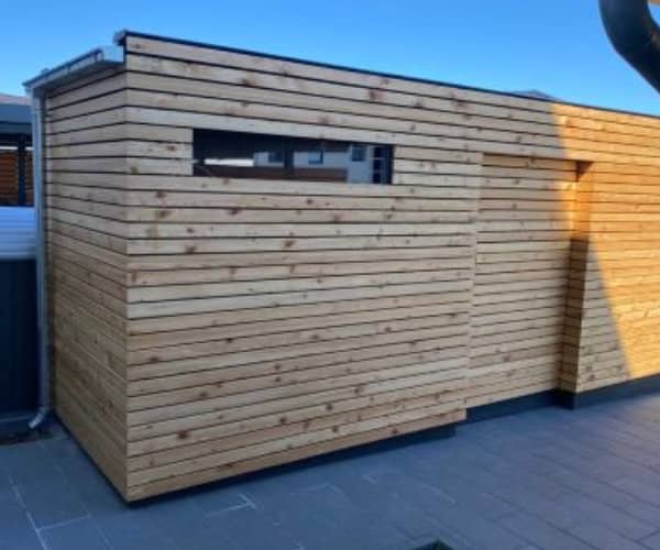Seitenansicht eines modernen Fahrradschuppens aus Holz mit klaren Linien, gefertigt von unserer Zimmerei.