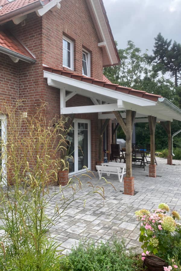 Seitenansicht einer Terrassenüberdachung aus Holz mit offener Konstruktion und stabilen Holzstützen