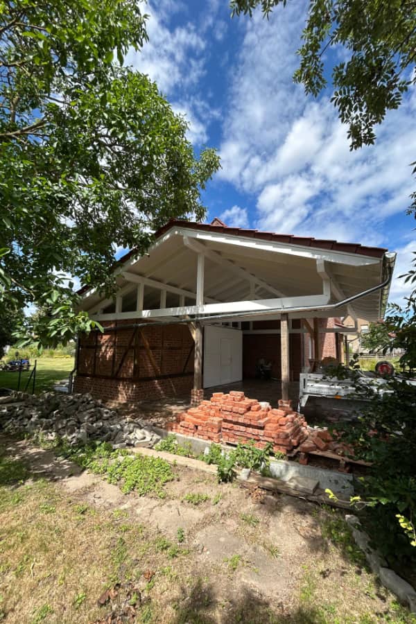 Terrassenüberdachung im Bau mit sichtbarer Holzkonstruktion und vorbereiteten Anschlüssen am Wohnhaus