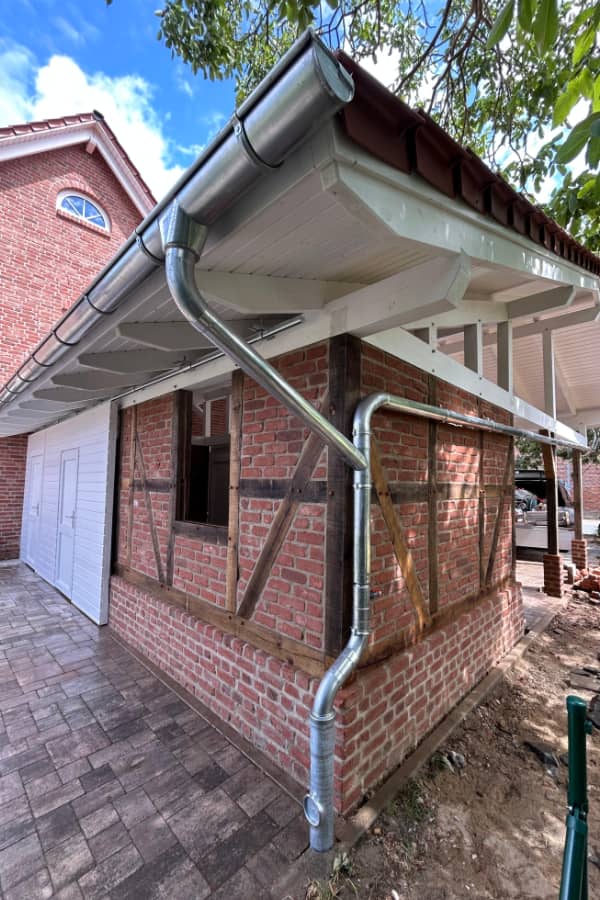 Seitenansicht eines Carports mit integrierter Dachentwässerung und traditioneller Holzbauweise