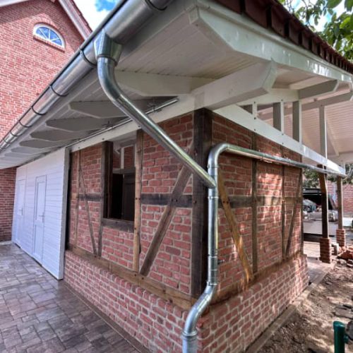 Seitenansicht eines Carports mit integrierter Dachentwässerung und traditioneller Holzbauweise